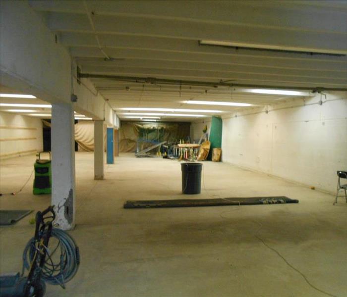 A large, well-lit facility basement containing a dehumidifier and other drying equipment.