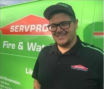 Male SERVPRO technician in front of van smiling at the camera.