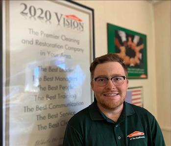 Man in green SERVPRO polo standing in front of 2020 Vision poster.