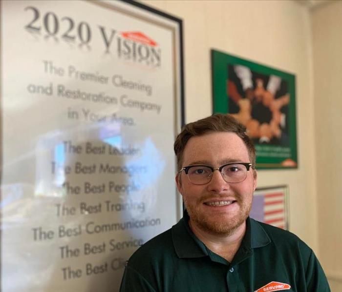 Male SERVPRO employee smiling in front of 2020 Vision poster.