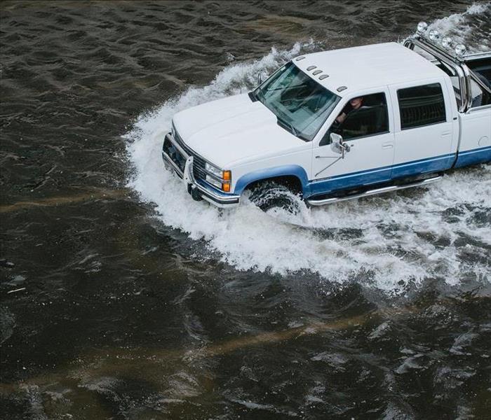 White pickup truck driving through flood waters.